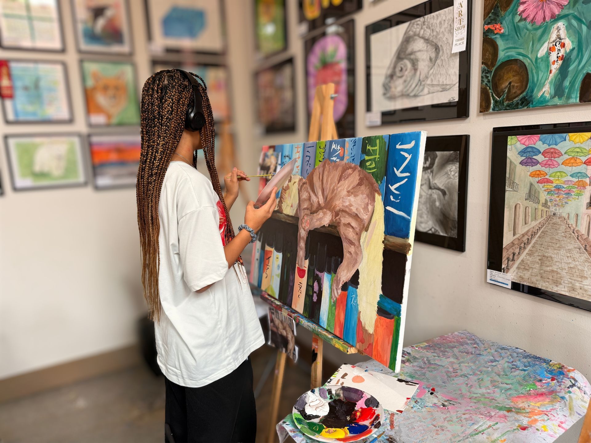 Artist painting a colorful canvas in a gallery with framed artwork on the walls.