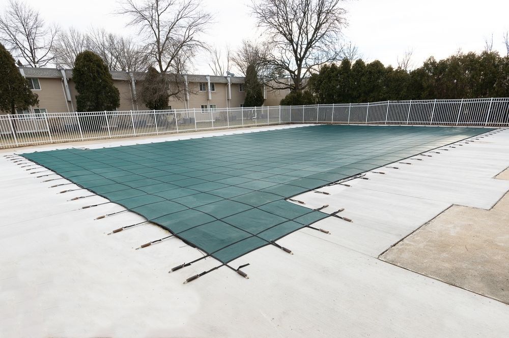 A large swimming pool in a backyard with a ladder and umbrella.