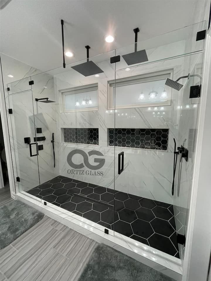 A bathroom with a walk in shower and black tiles.
