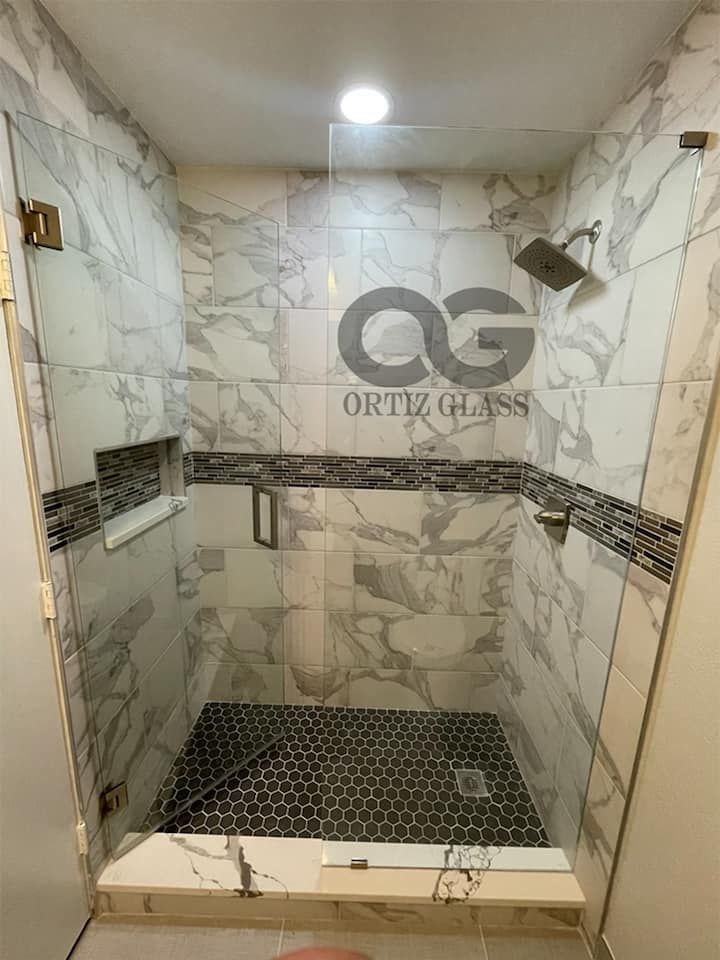 A bathroom with a walk in shower with a glass door.