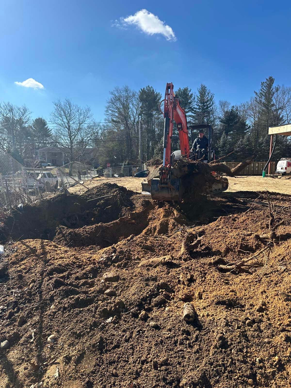 A small excavator digging in brown soil on a sunny day.