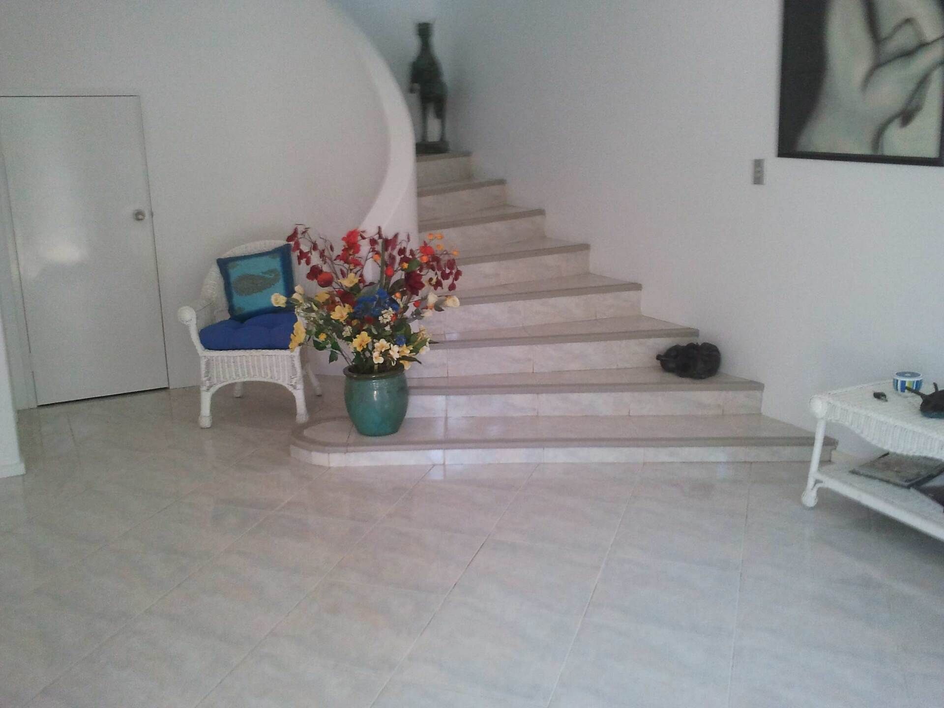 A Living Room With Stairs Leading Up to the Second Floor and a Vase of Flowers — Alice Springs Carpet Cleaning In Gillen, NT