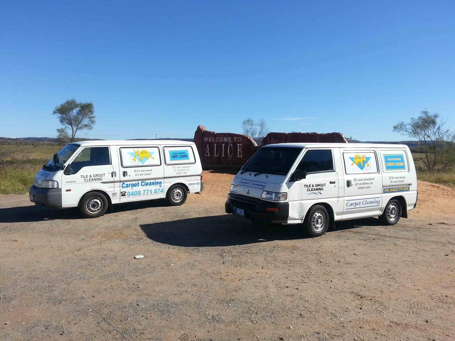 Two White Vans Are Parked Next to Each Other on a Dirt Road — Alice Springs Carpet Cleaning In Gillen, NT