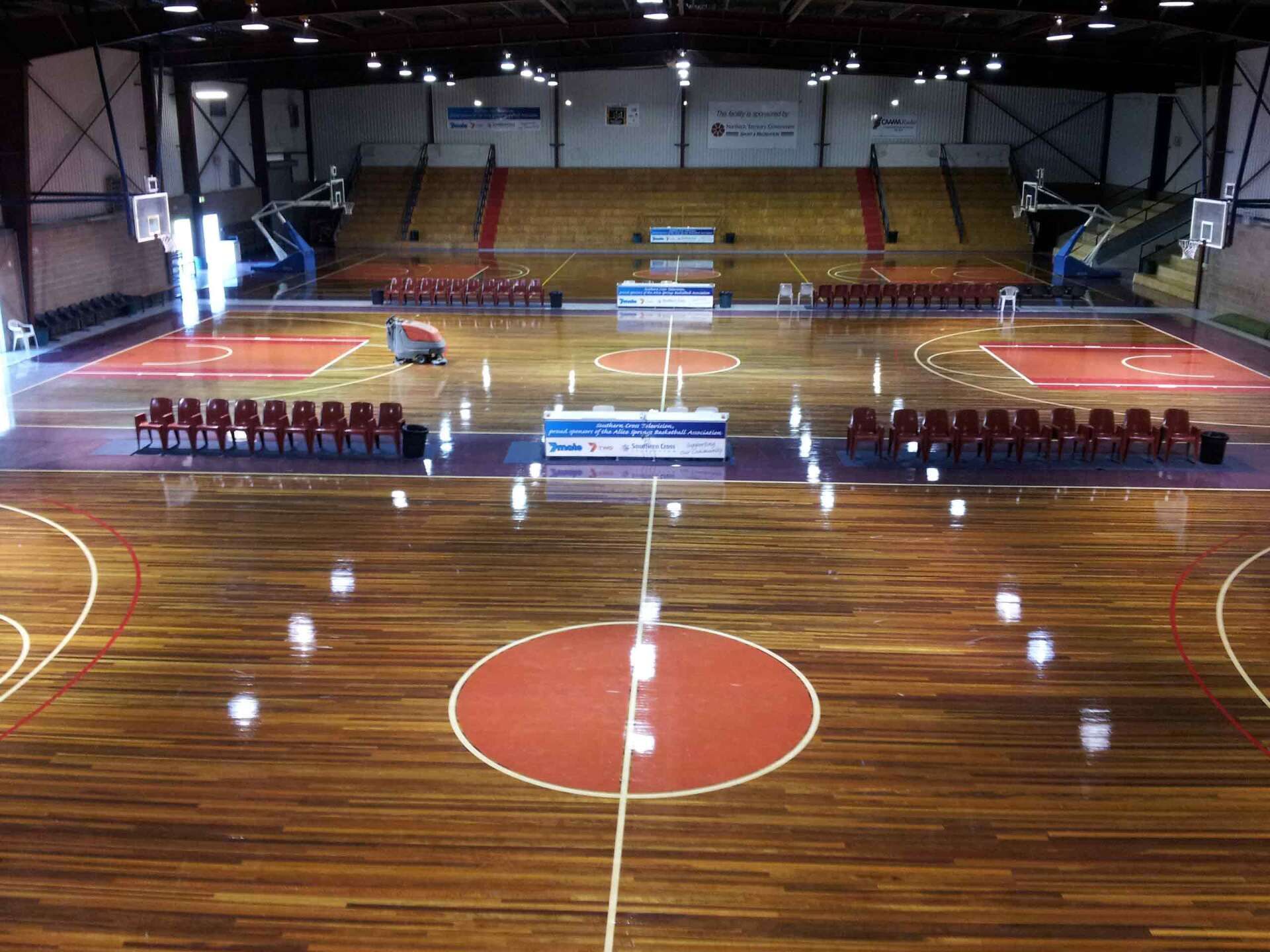 A Large Indoor Basketball Court With a Wooden Floor — Alice Springs Carpet Cleaning In Gillen, NT