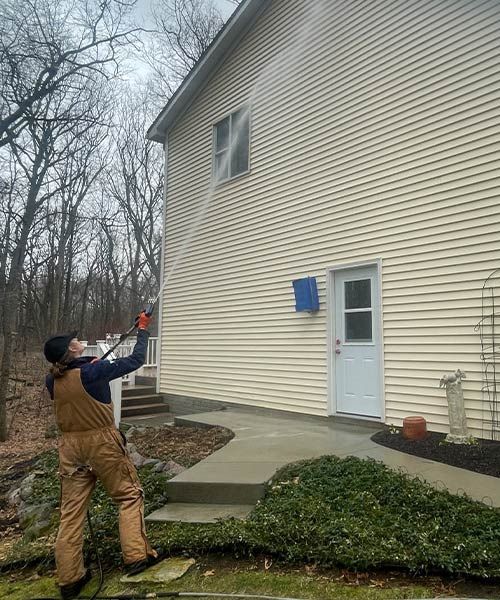 a man on a ladder is cleaning the roof of a blue house .