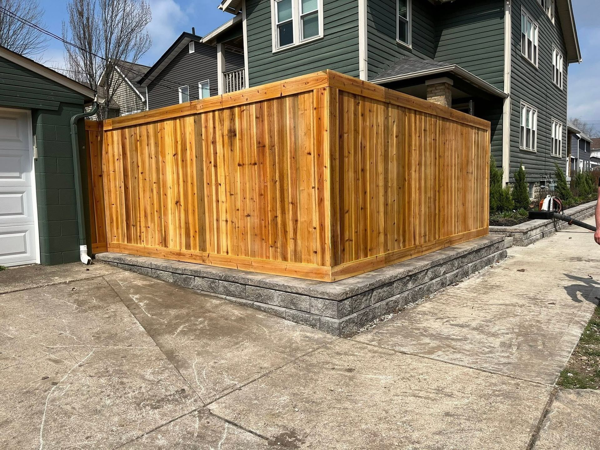 Wooden privacy fence enclosing a corner patio beside a house and driveway