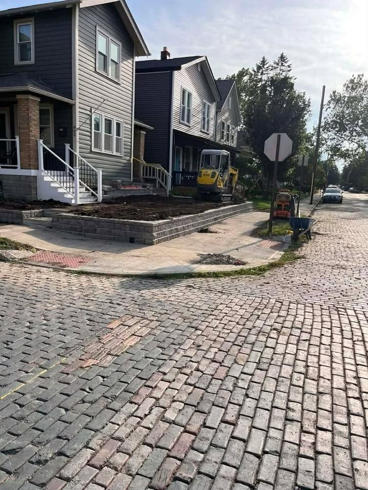 Cobblestone street with dark houses, a yellow bicycle, and a stop sign on a sunny residential corner