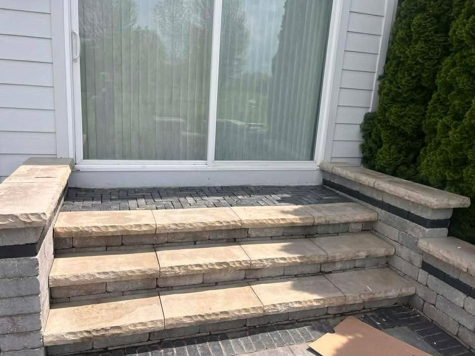 Stone front steps leading to a sliding glass door beside a white house facade