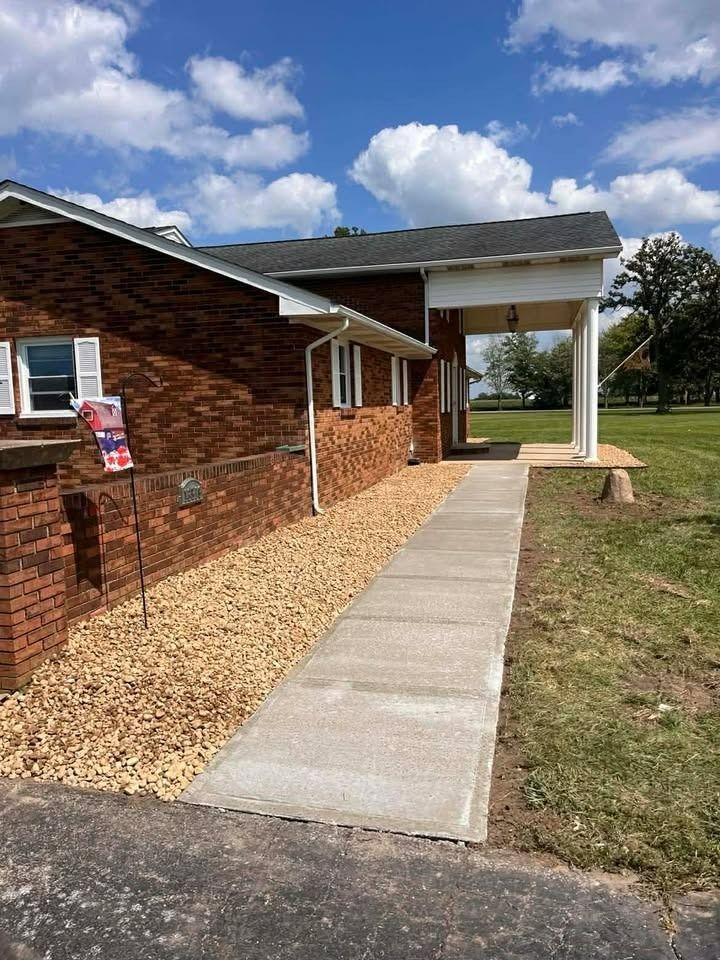 Brick building with a concrete walkway leading to a covered entrance under a blue sky.