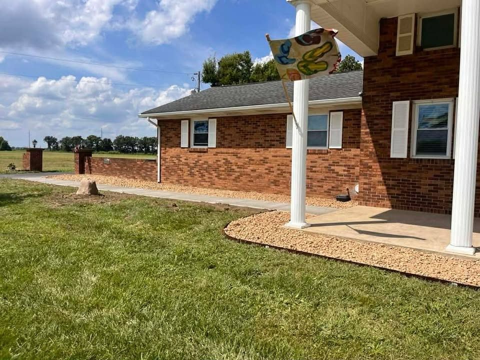 Brick house with white porch columns, a lawn, and a colorful birdhouse in the yard