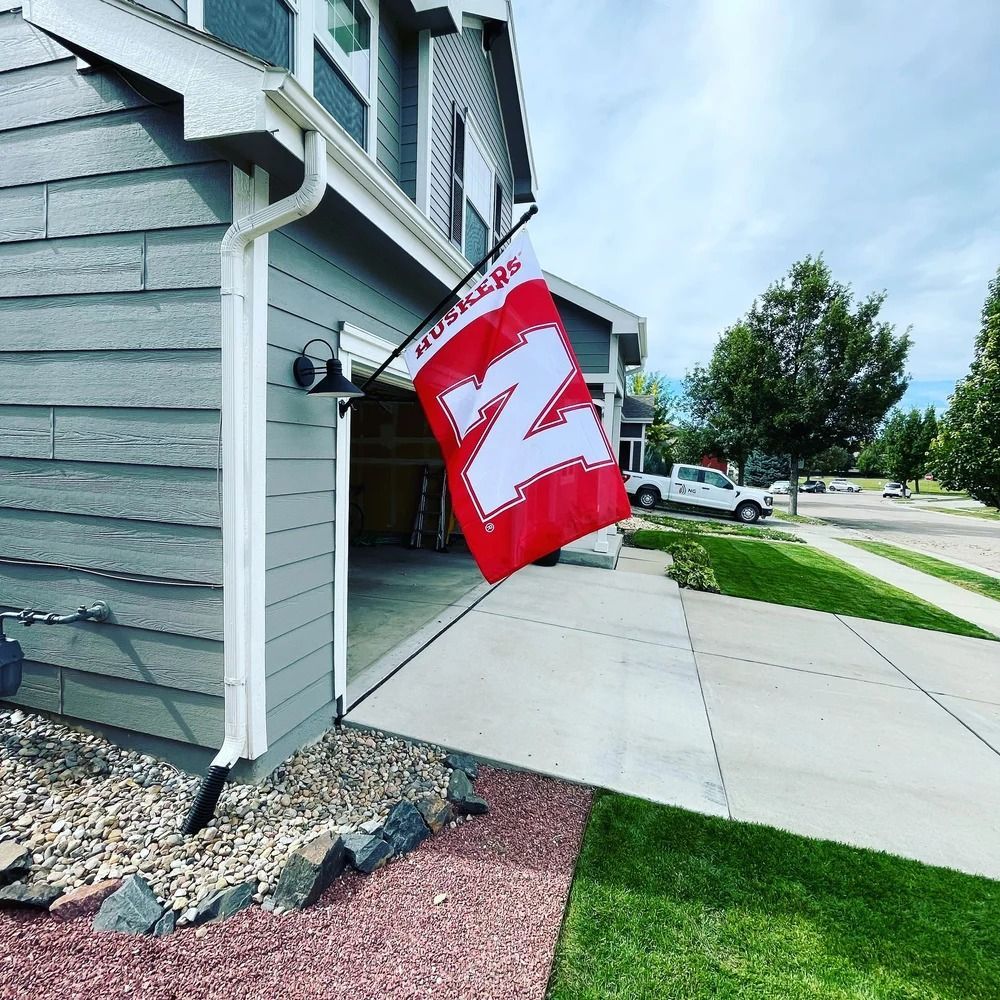 Red Kansas flag hanging outside a house beside a sidewalk and driveway.