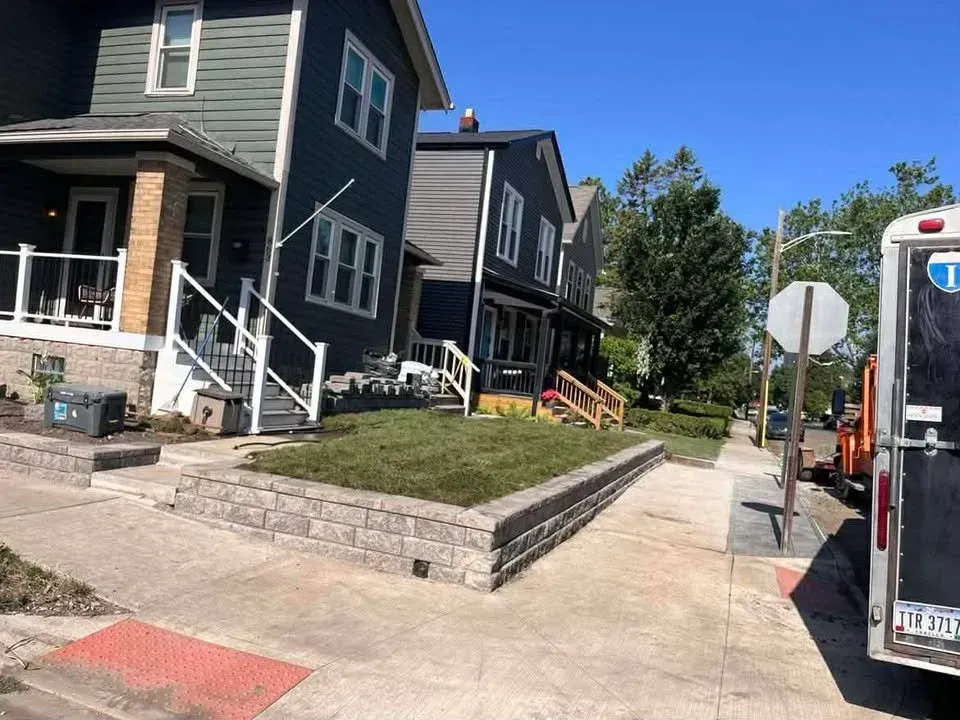 Residential street with dark houses, a sidewalk, and a parked truck on a sunny day