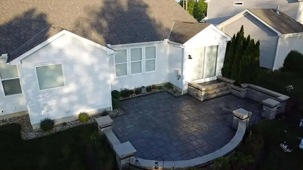 White house exterior with a curved dark patio and landscaped yard in daylight