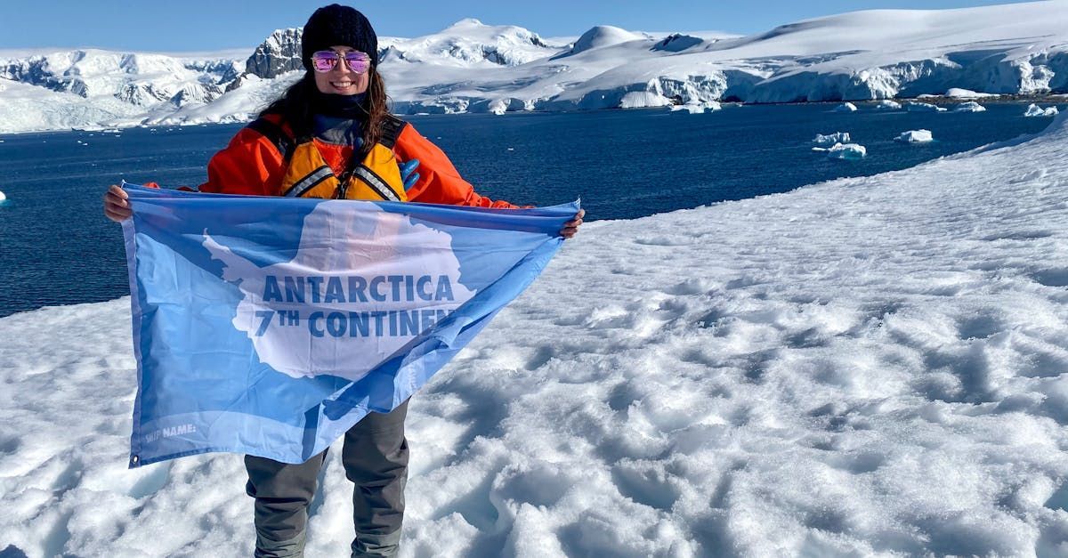 A woman is standing in the snow holding a flag.
