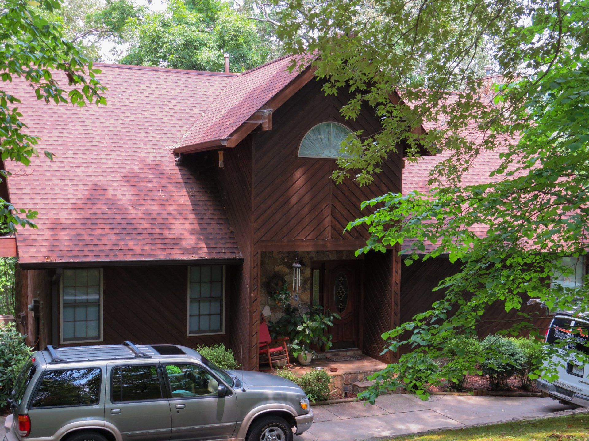 A car is parked in front of a house with a red roof