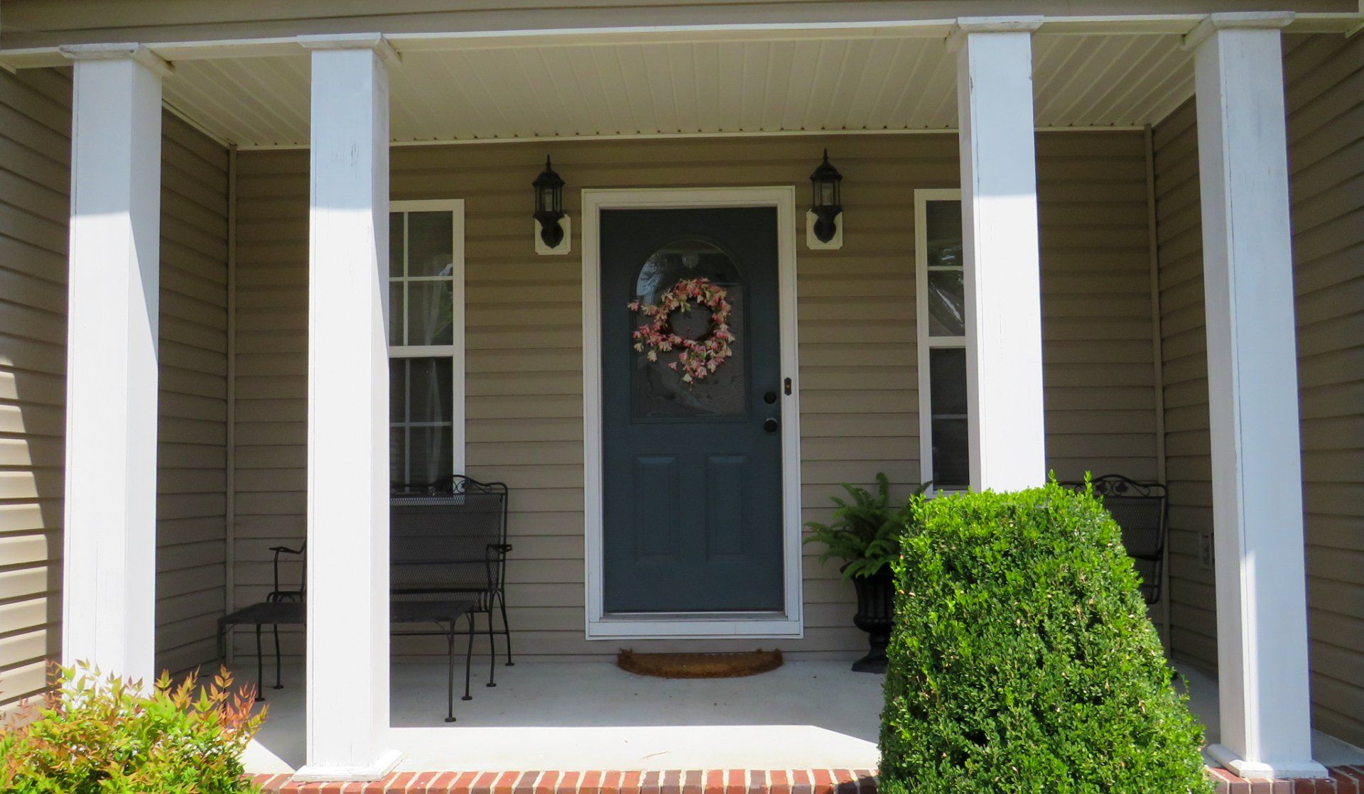 The front porch of a house with a wreath on the door