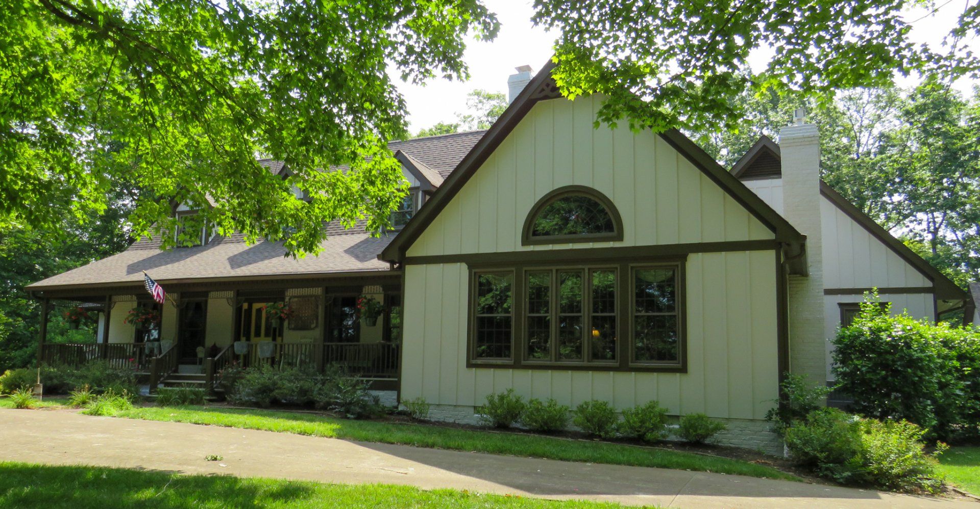 A white house with a brown roof is surrounded by trees