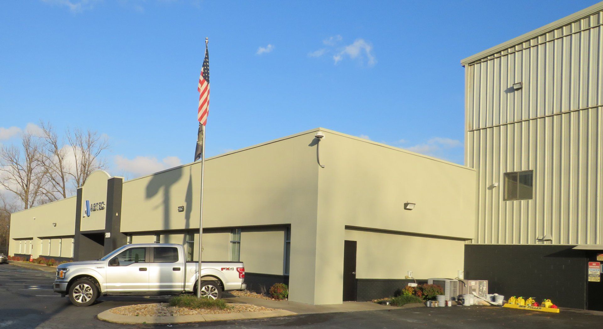 A white truck is parked in front of a building with an american flag.