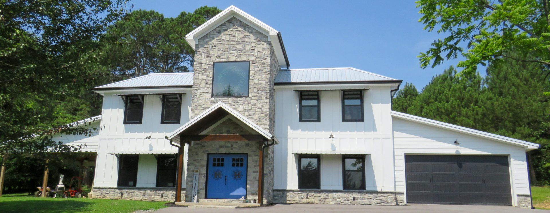 A large white house with a blue door is surrounded by trees.