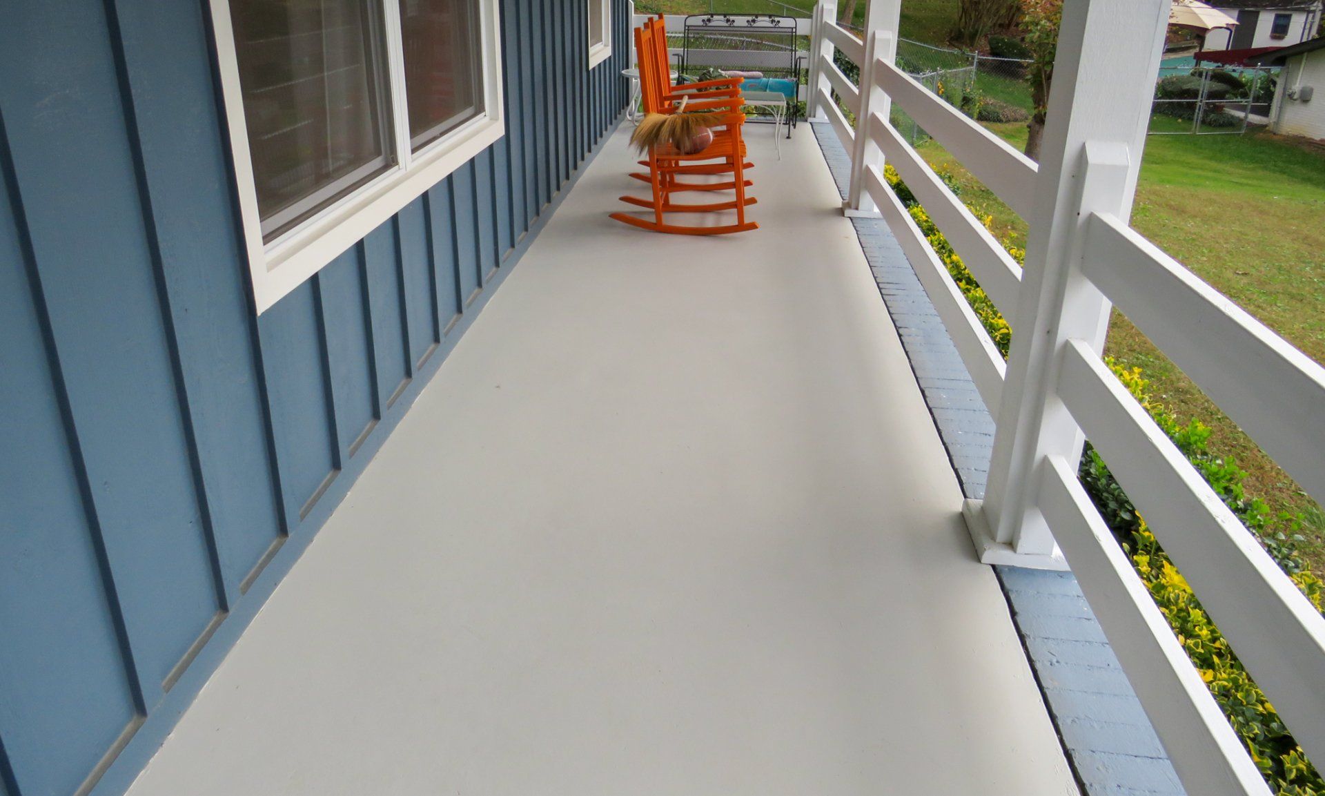 A porch with rocking chairs and a white railing