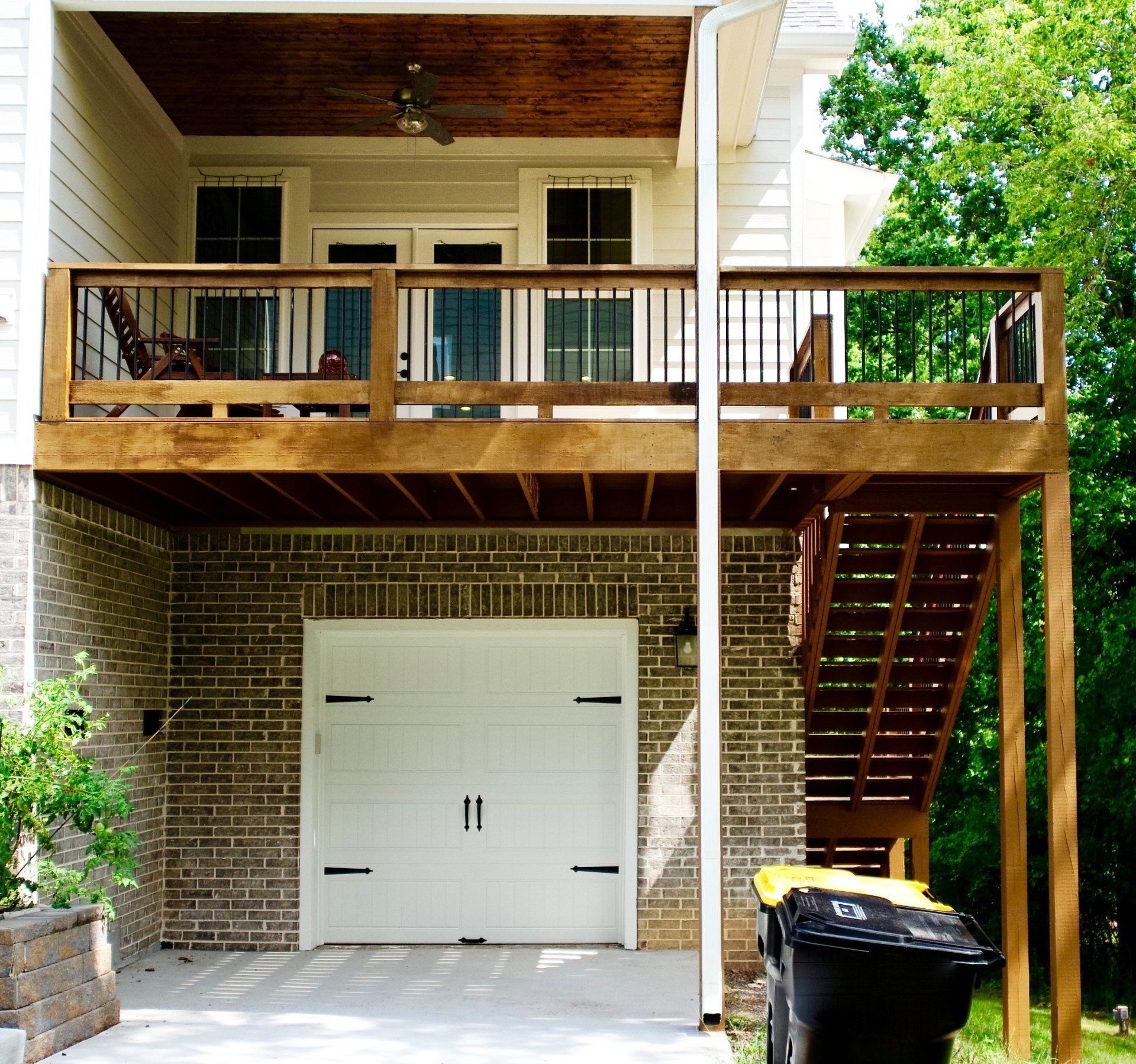 A white garage door with a wooden deck above it
