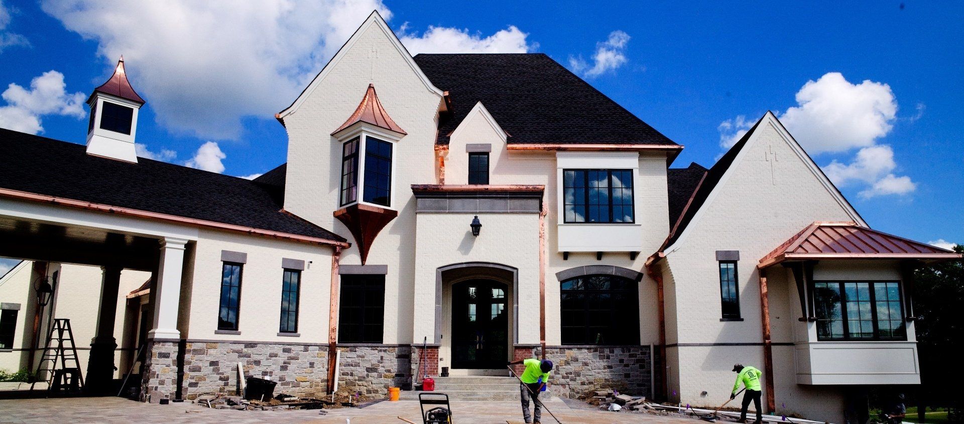 A large white house with a black roof is being built.