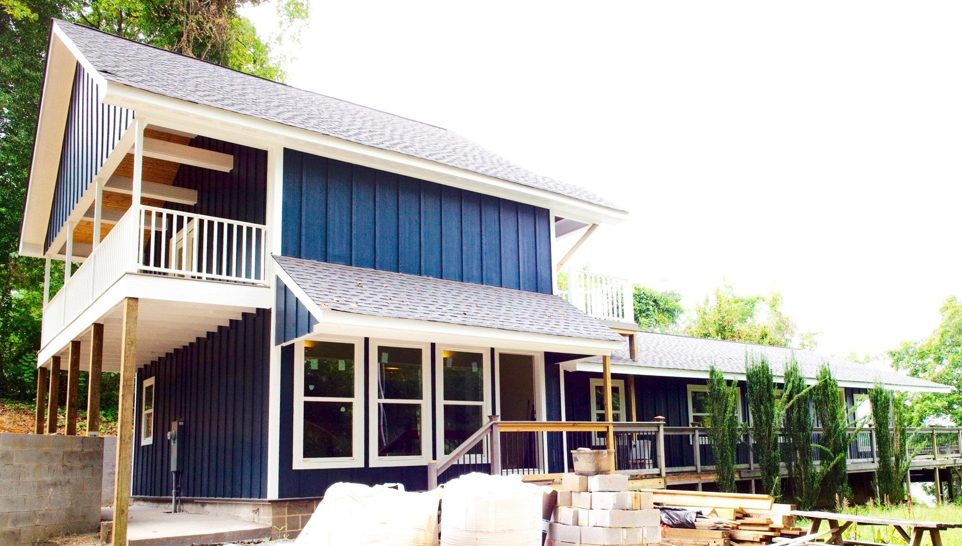 A blue house with a white porch is under construction.
