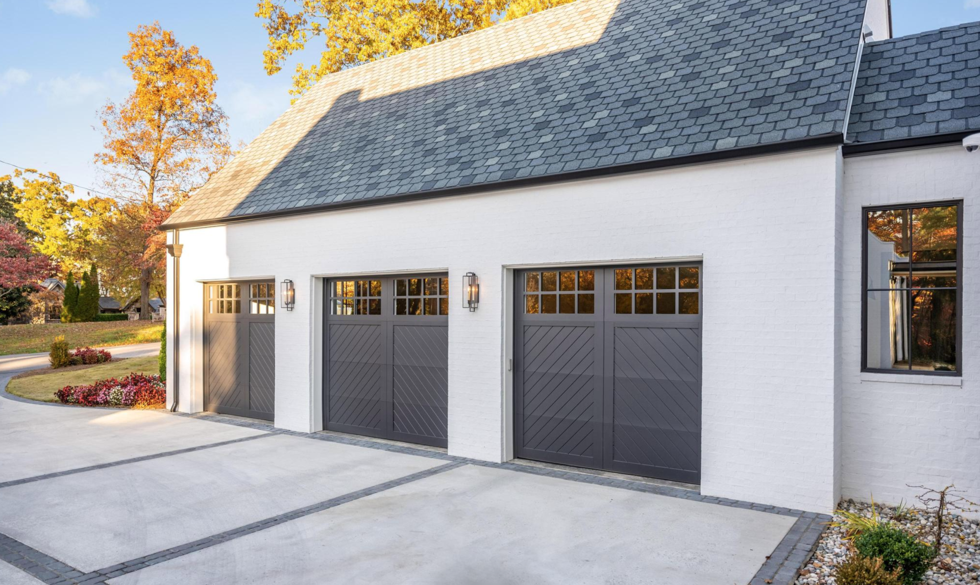 A white house with three garage doors and a driveway.