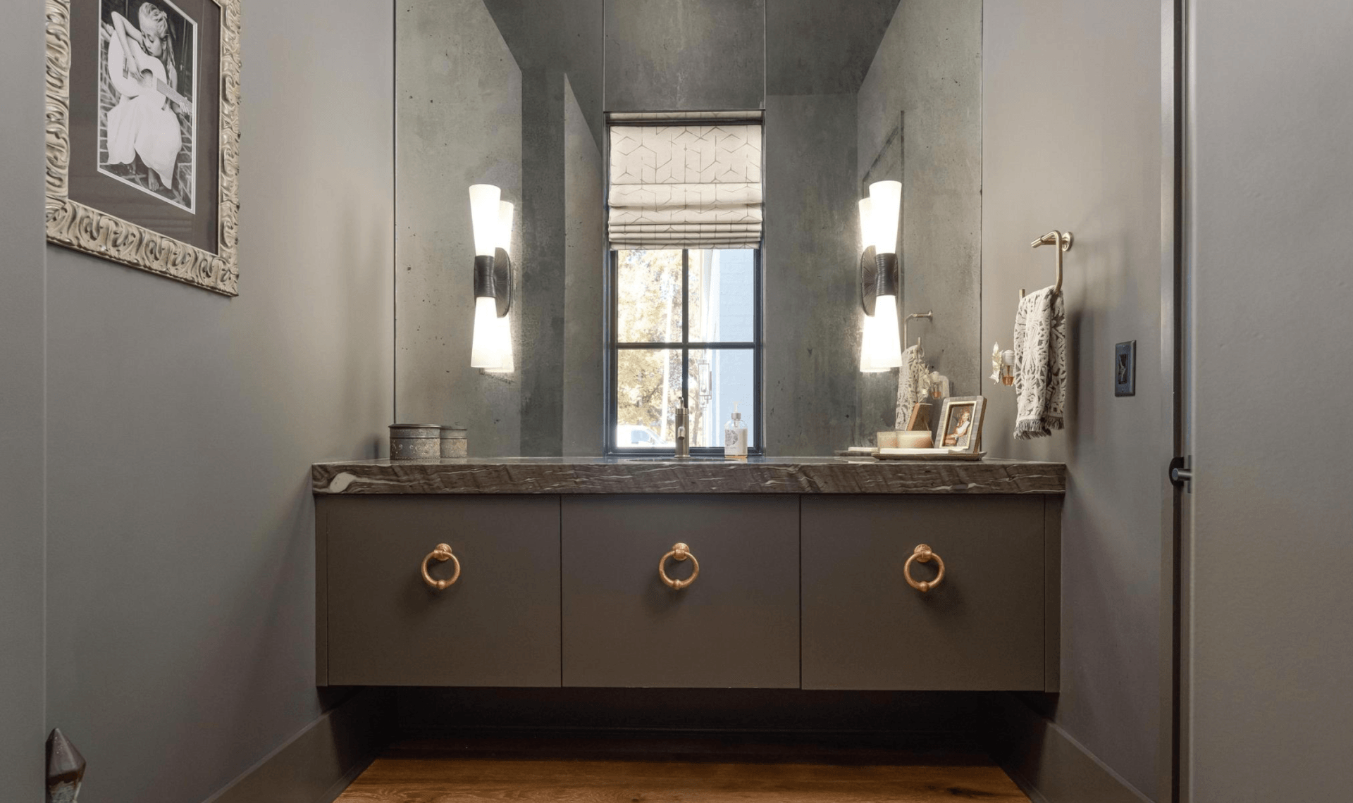 A bathroom with a sink , mirror and window.