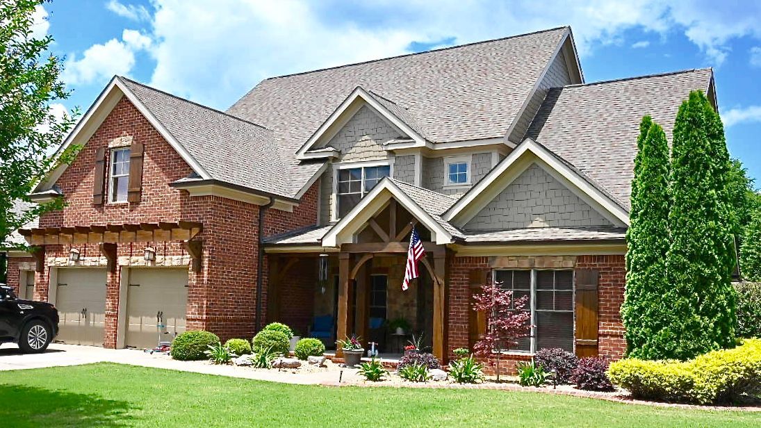 A large brick house with a car parked in front of it on a sunny day.
