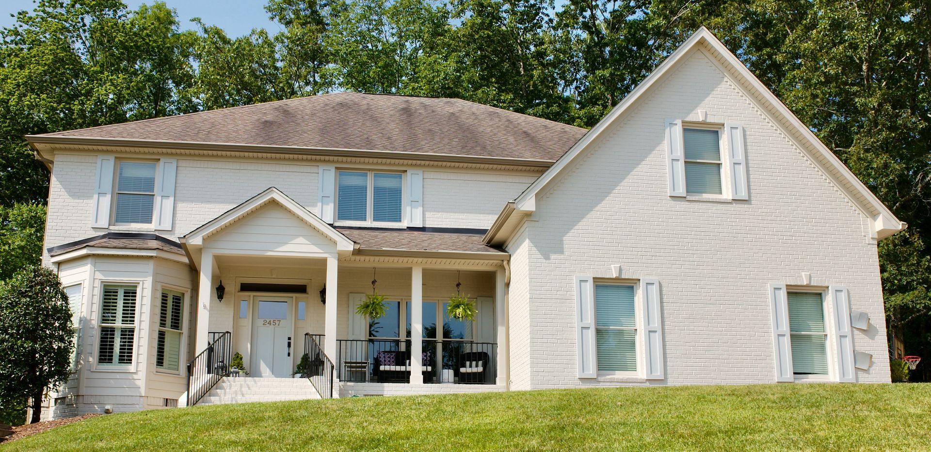 A large white house is sitting on top of a grassy hill.