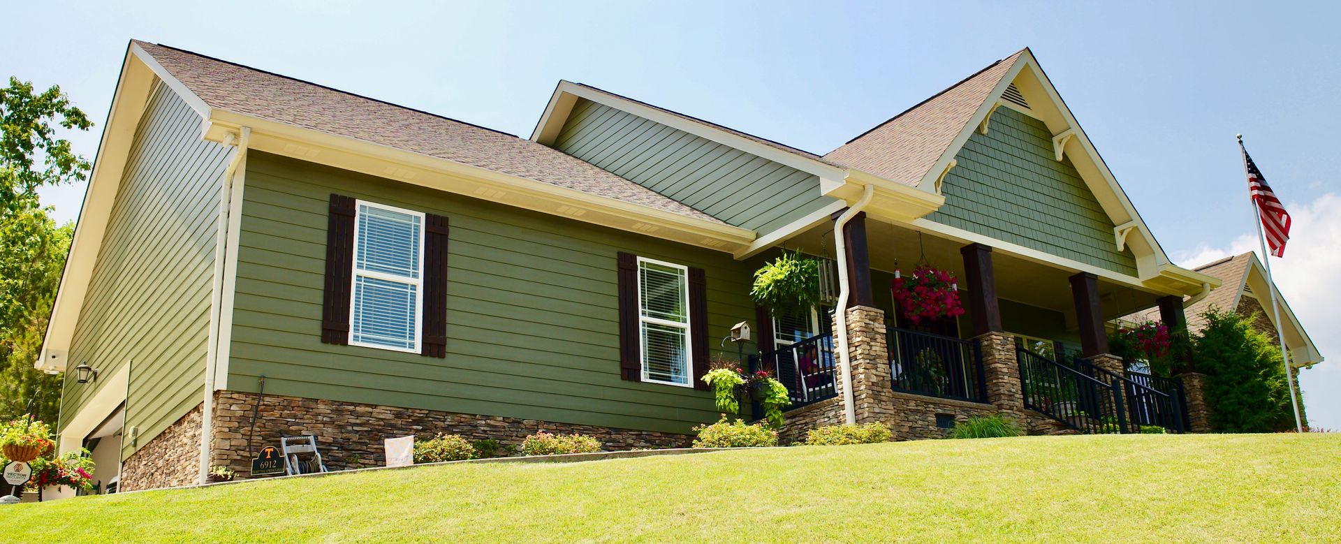 A large green house with a porch and an american flag