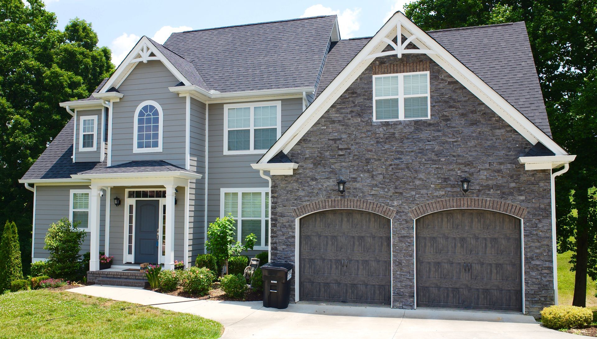 A large gray house with two garage doors and a gray roof