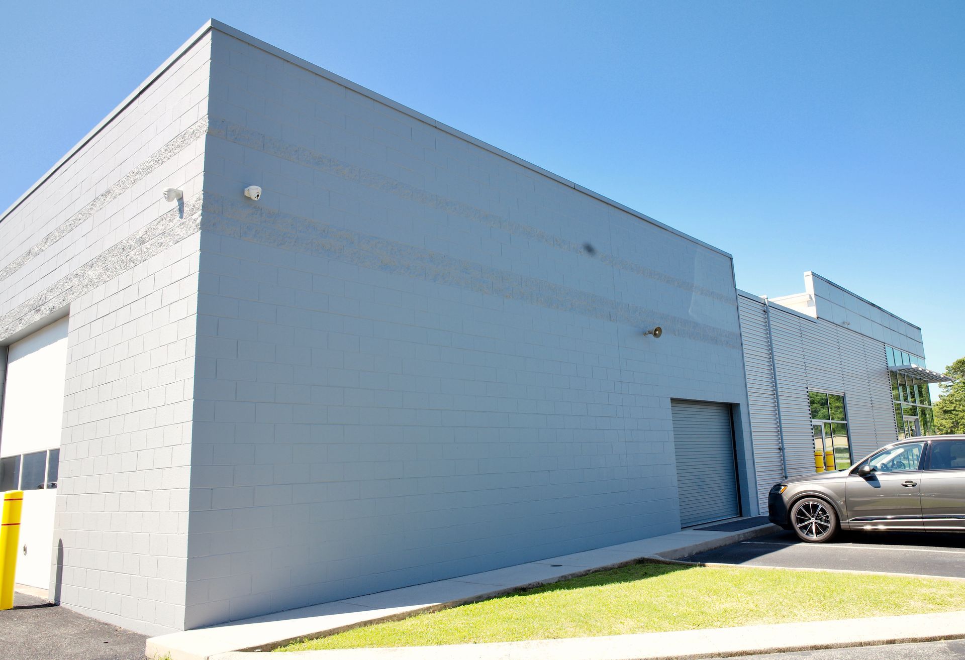 A car is parked in front of a grey building