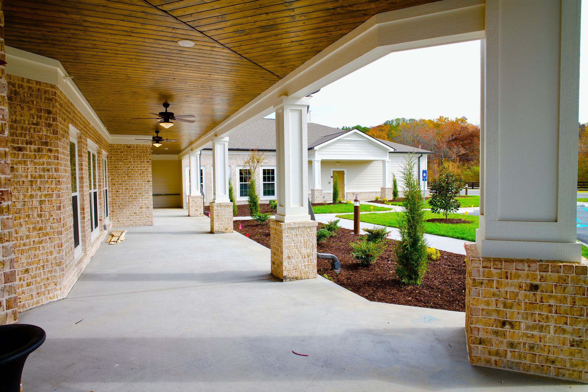 A long covered walkway leading to a house with a ceiling fan.