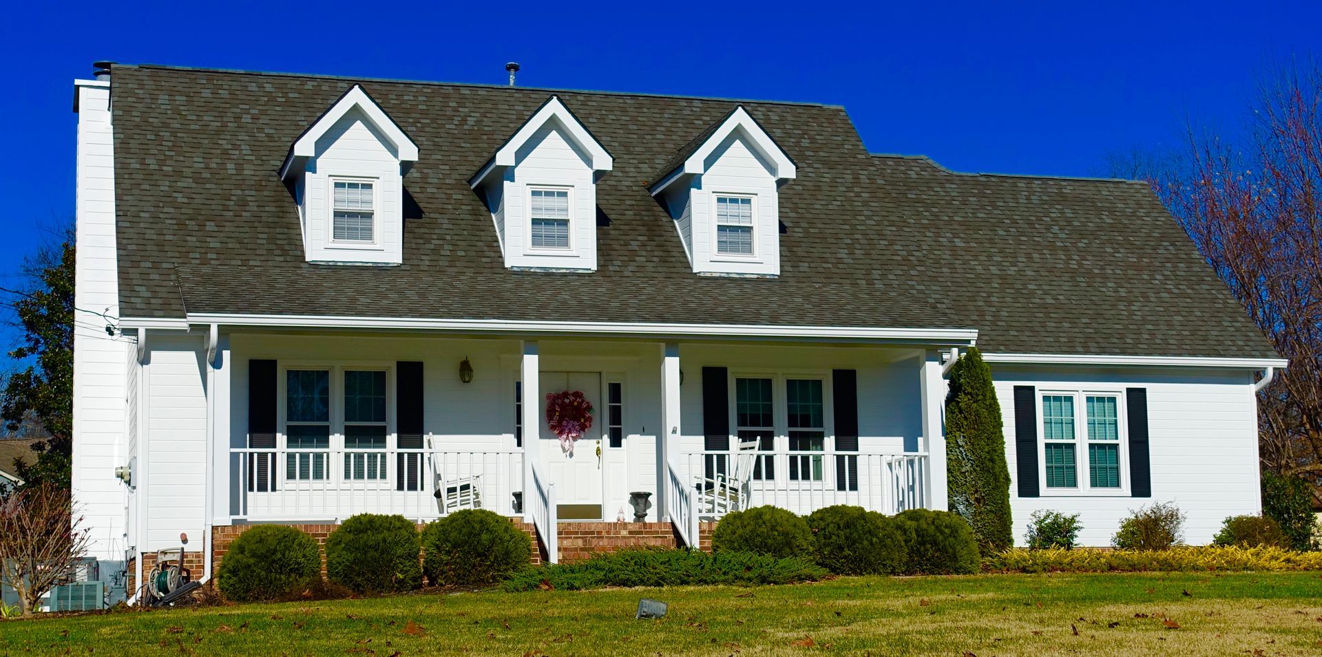 A large white house with a gray roof and black shutters