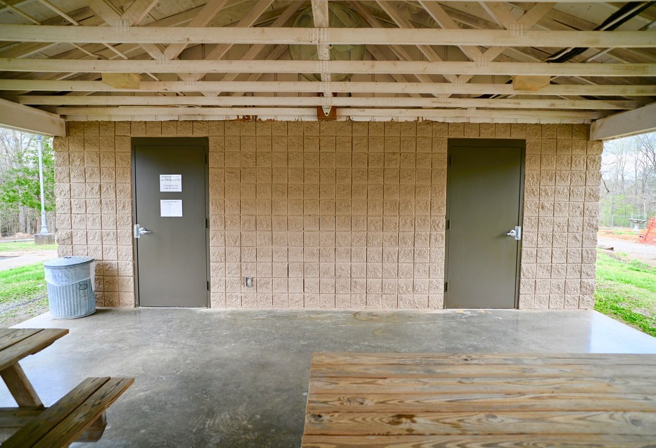 A brick building with two doors and a picnic table underneath it.