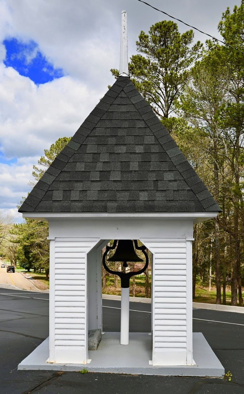 A small white building with a bell on top of it