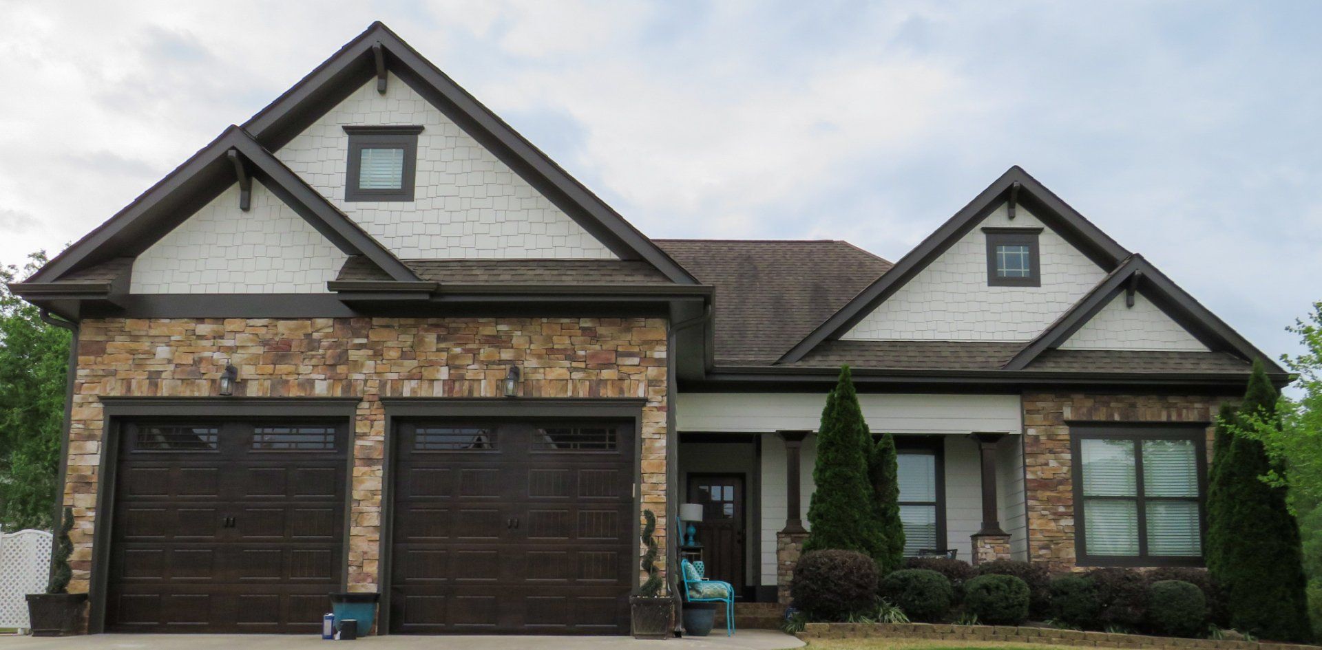 A large house with a brown garage door and a stone facade.