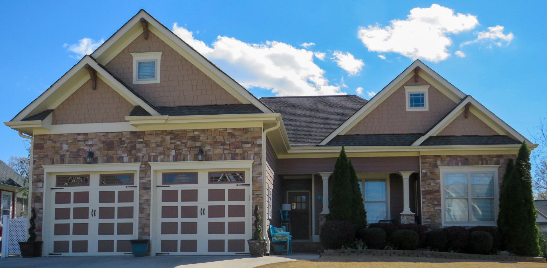 A house with two garage doors and a blue sky in the background