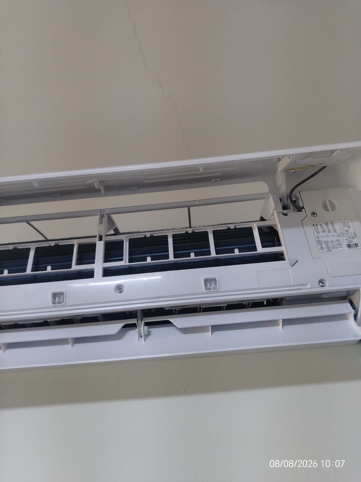 Aire acondicionado mural abierto con panel frontal levantado, que deja ver las rejillas de ventilación y los filtros.