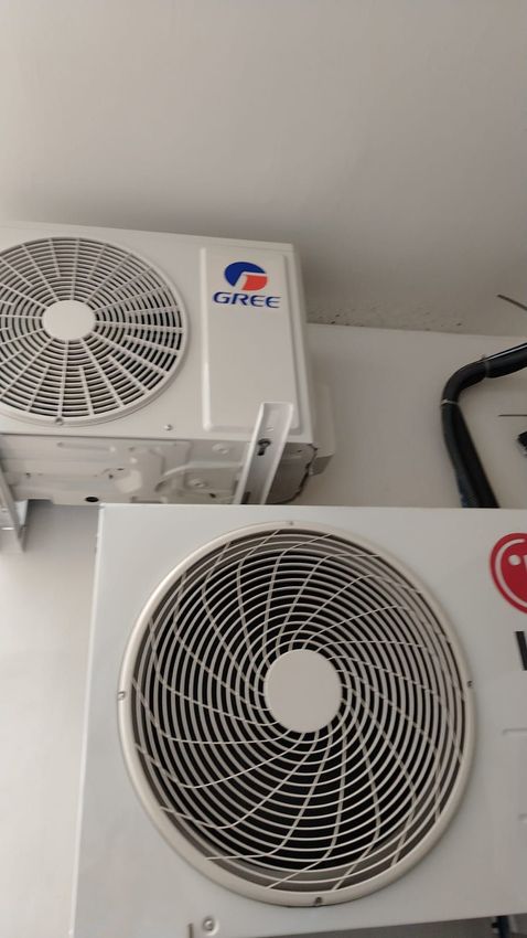 Dos unidades exteriores de aire acondicionado blancas montadas en una pared, una encima de la otra.