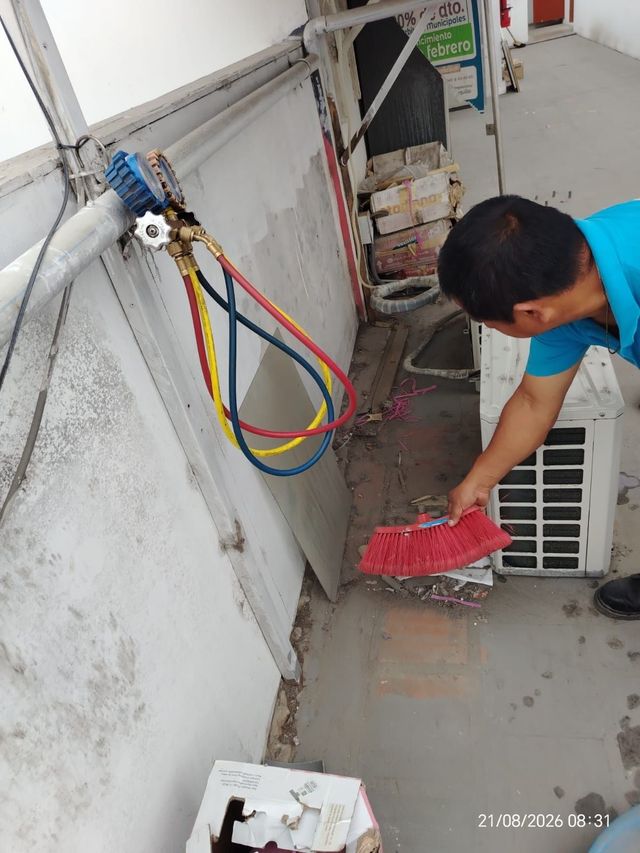 Una persona barre escombros junto a cables montados en la pared y un medidor eléctrico exterior.