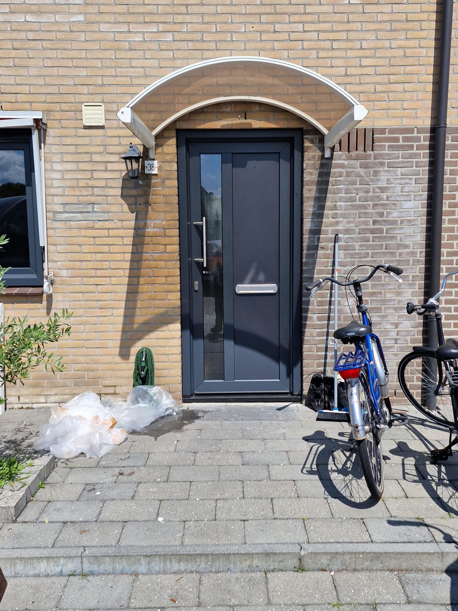 voordeur Een fiets staat geparkeerd voor een bakstenen gebouw.
