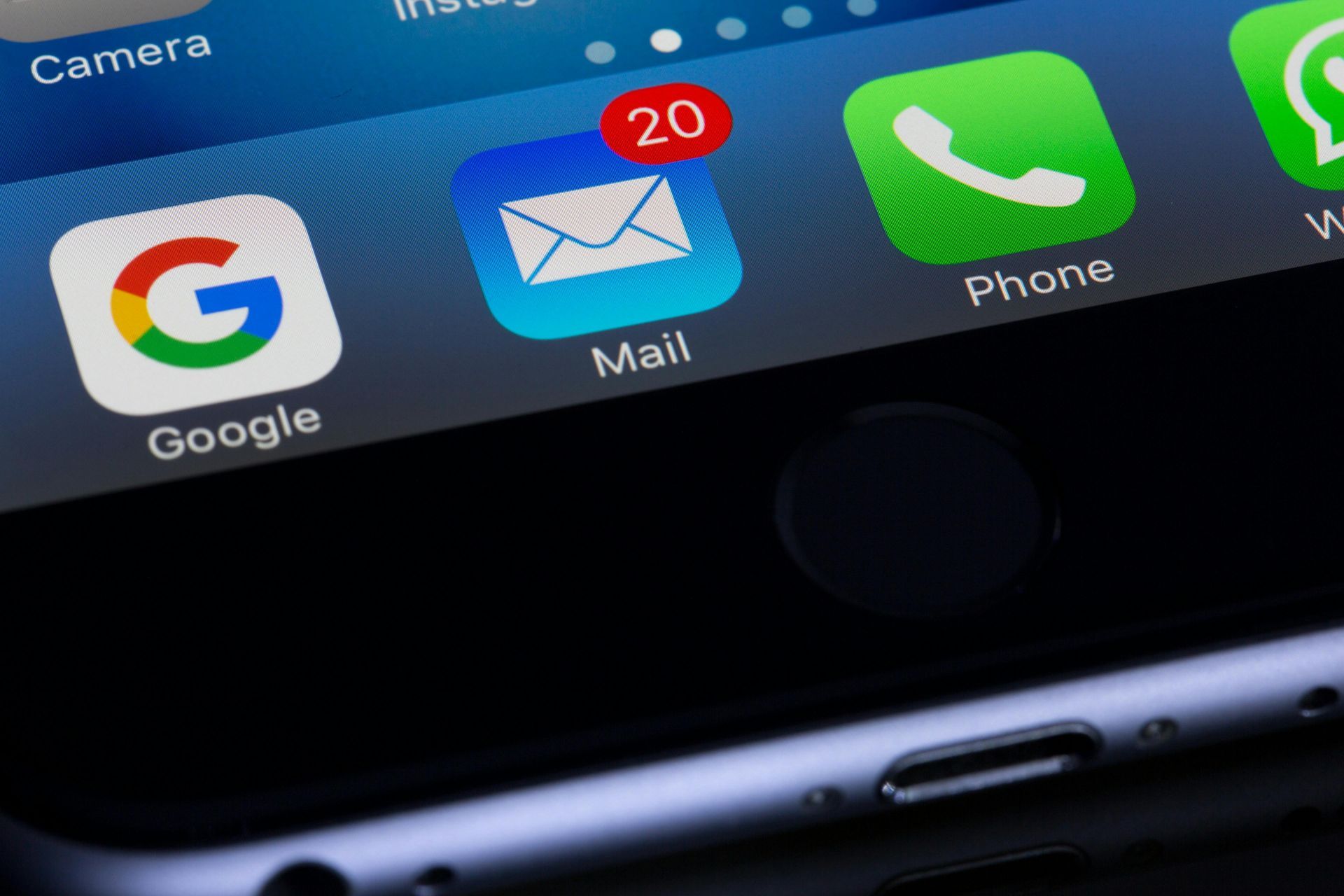 Close-up of a smartphone screen showing app icons: Google, Mail (20 unread emails), Phone, and a white app.