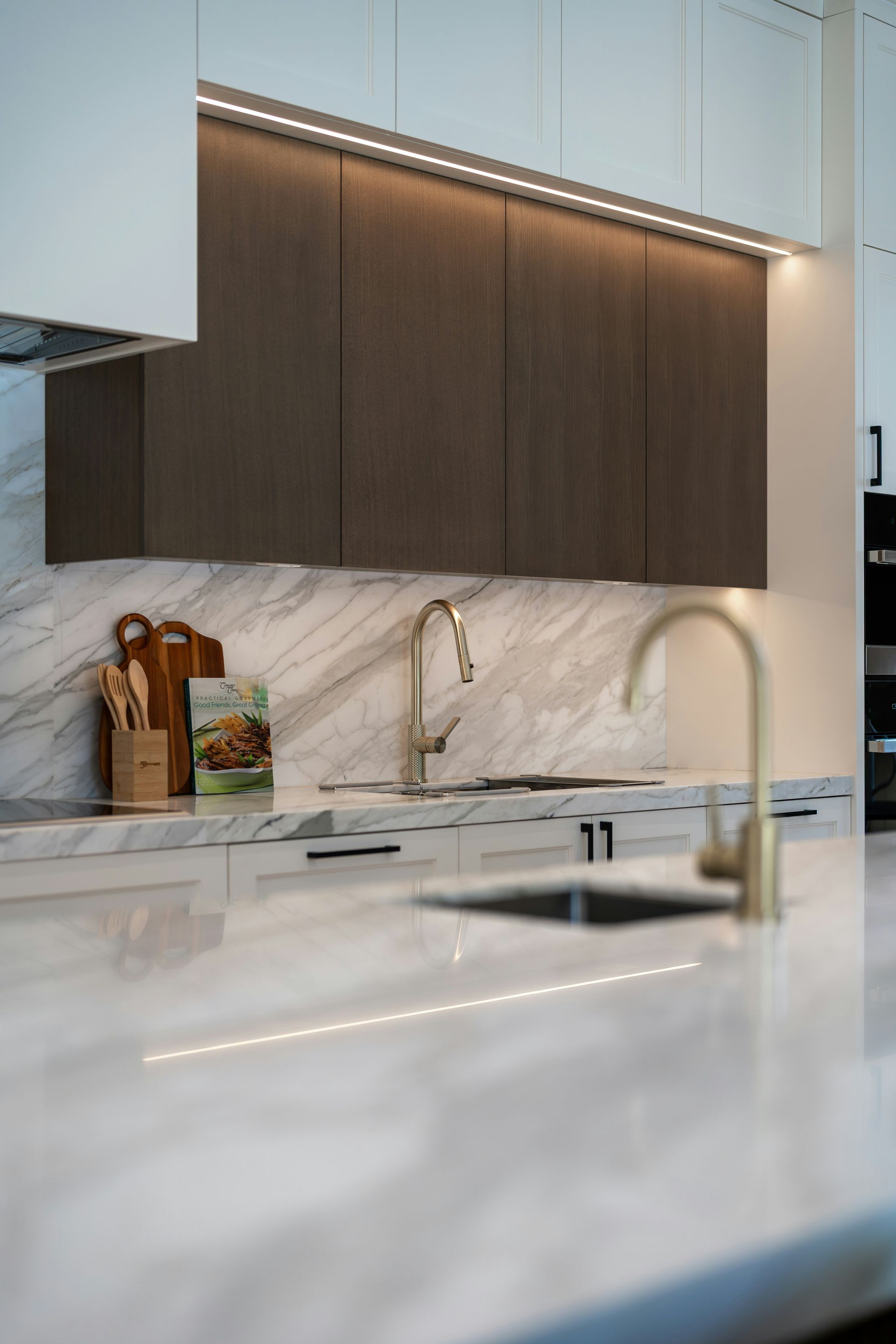 Modern kitchen with marble backsplash, dark wood cabinets, and a white island countertop
