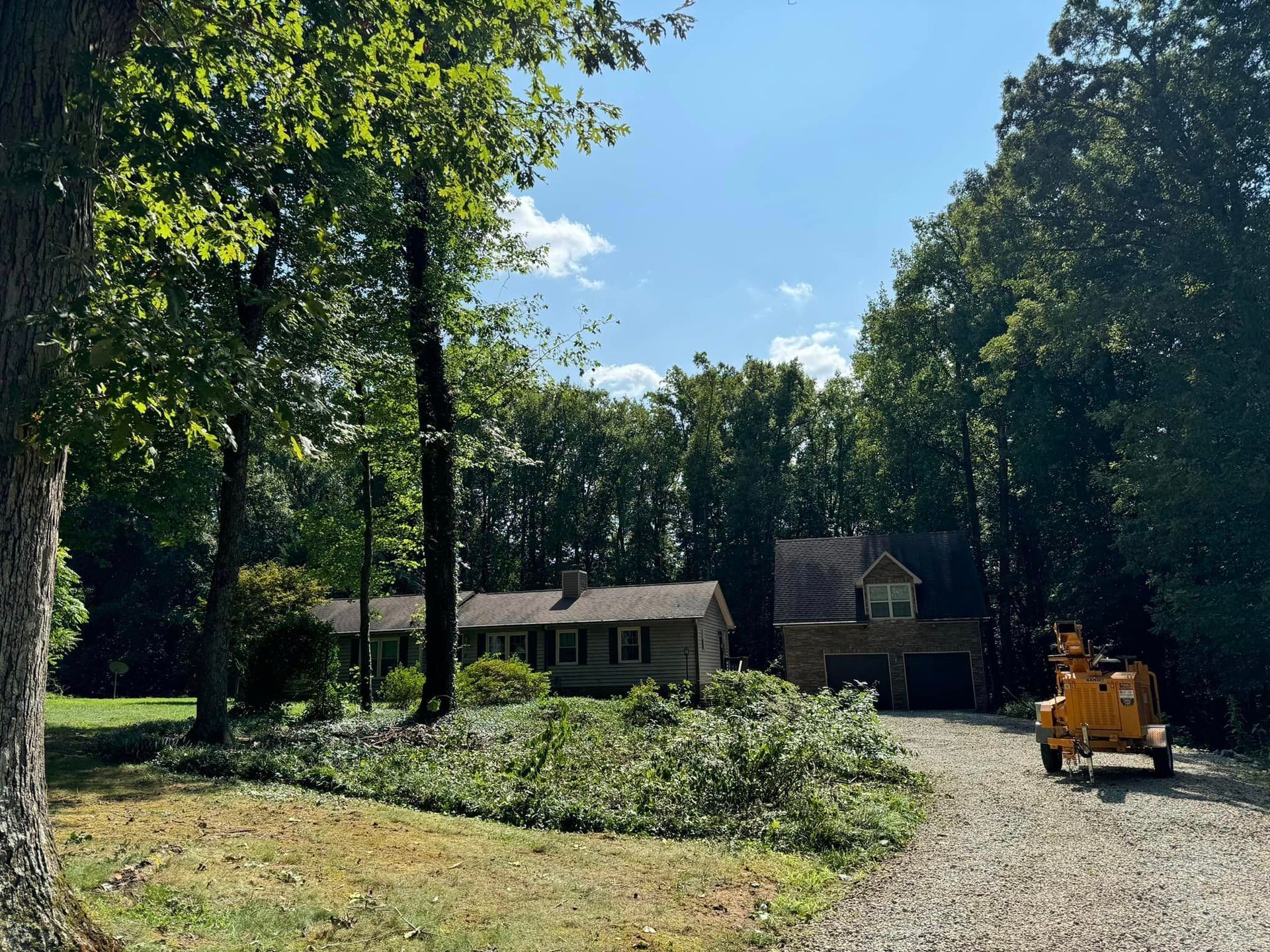 A yellow truck is parked in front of a house surrounded by trees.