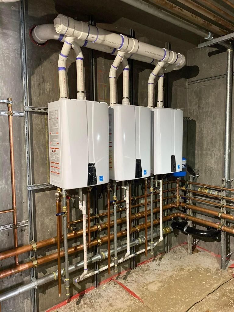 Three white wall-mounted boilers with copper pipes in a basement utility room