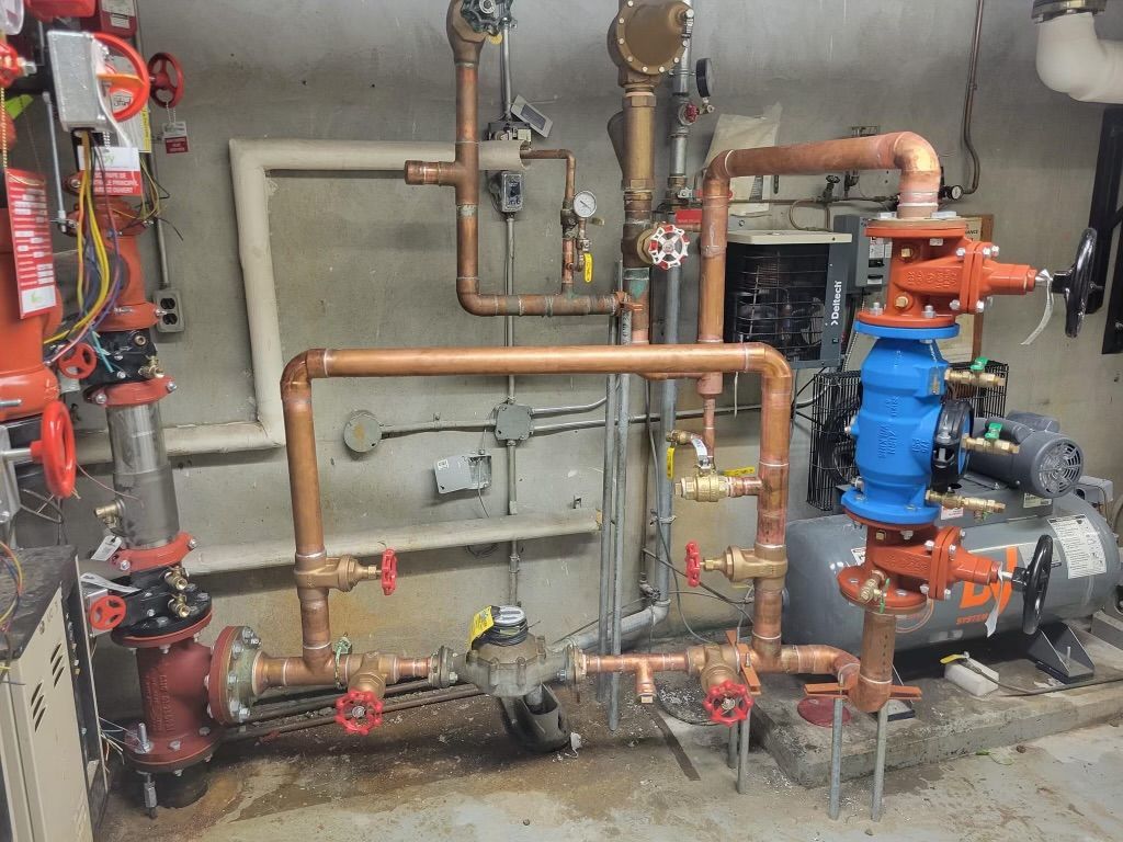 Copper and blue industrial piping with valves and gauges in a utility room