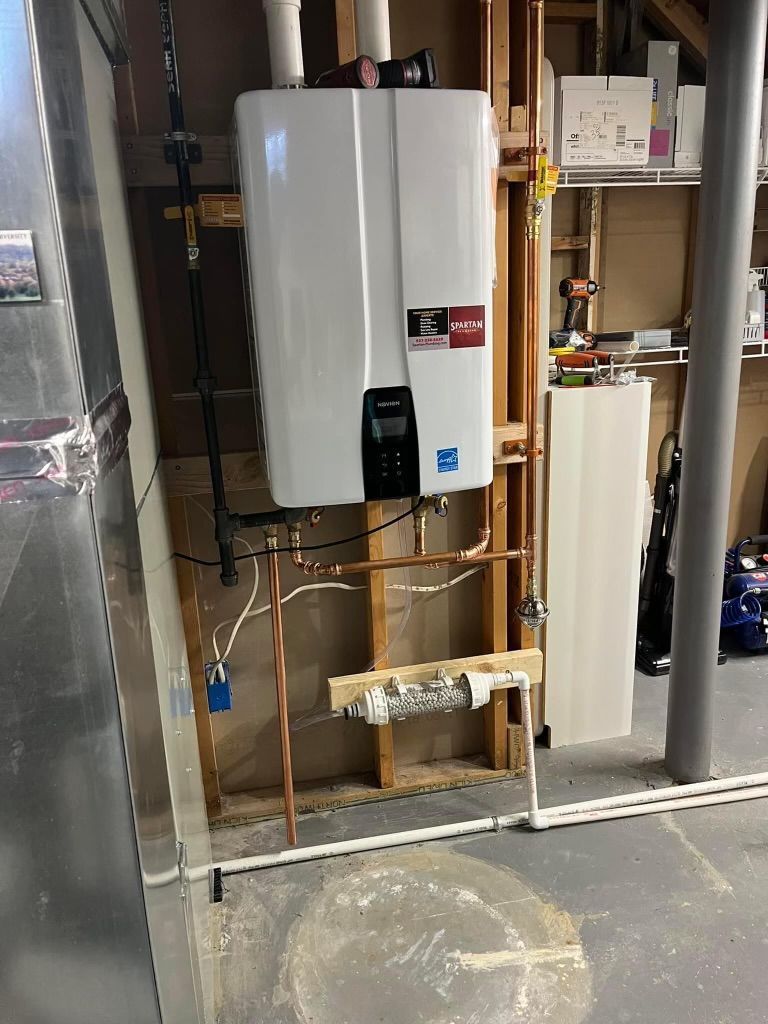 Utility room with wall-mounted tankless water heater, exposed copper pipes, and concrete floor.